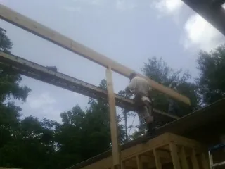 Carpenter setting a ridge beam over a new addition frame — Ice Dam Removal by Roofing Brothers in Eagle Bay