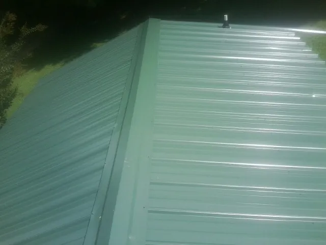 New green metal panels meeting at the ridge of a roof — Flat Roof Repair work by our crew in Eagle Bay