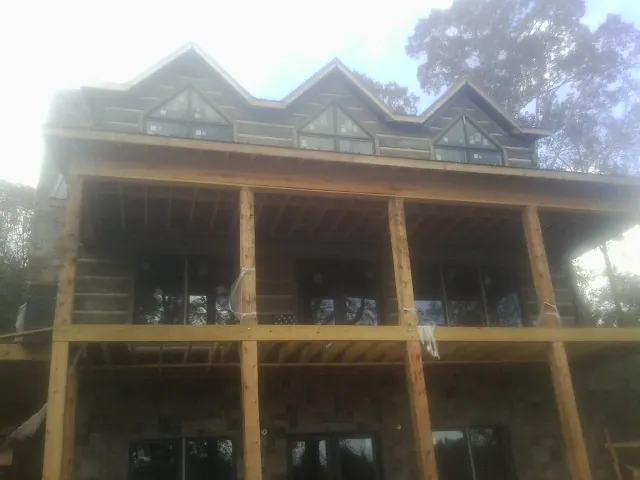 Dormers and porch framing on a large log home under construction — Roof Coating work by our crew in Eagle Bay