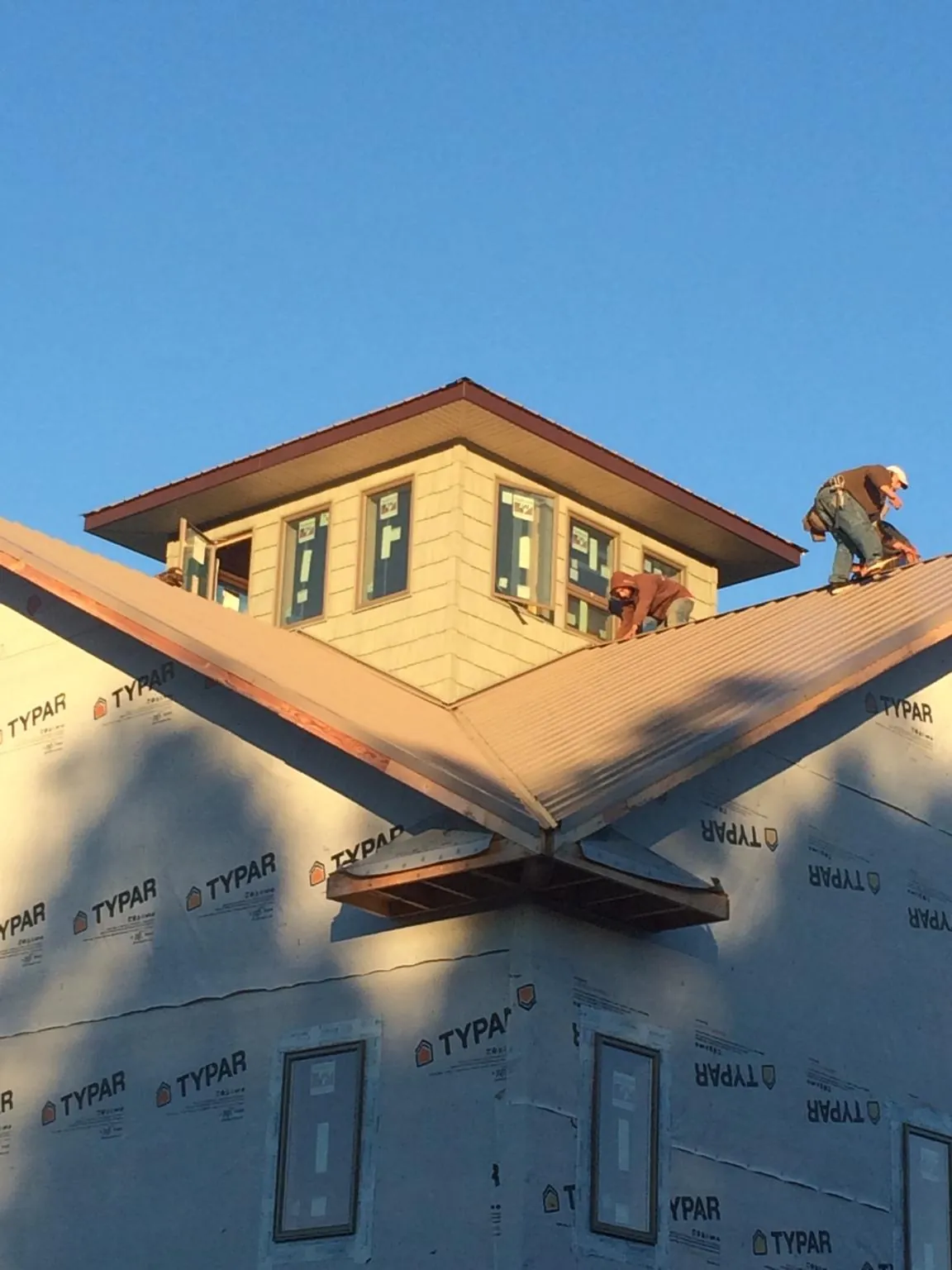 Roofers working around a rooftop cupola on a new metal roof at sunset — Roof Waterproofing in Eagle Bay by Roofing Brothers